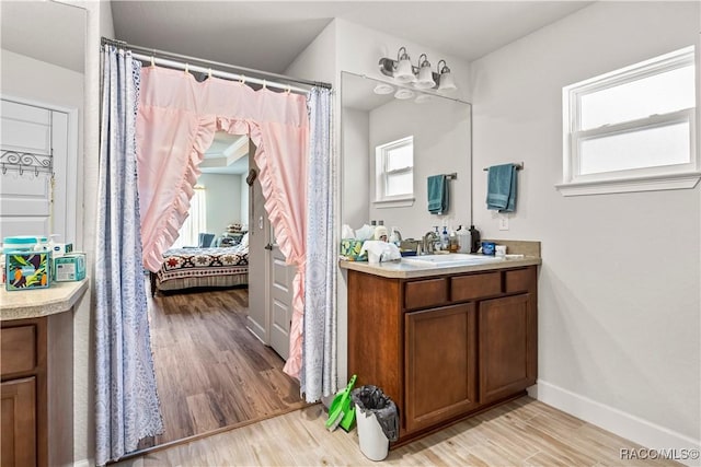 bathroom with connected bathroom, baseboards, vanity, and wood finished floors