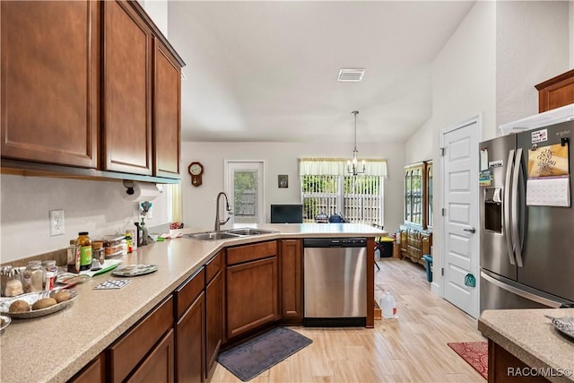 kitchen featuring a peninsula, a sink, visible vents, a notable chandelier, and appliances with stainless steel finishes