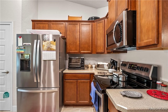 kitchen featuring light countertops, appliances with stainless steel finishes, a toaster, and brown cabinets