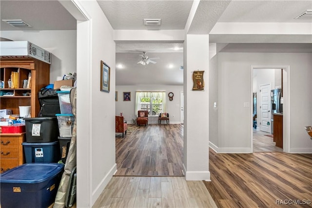 hall with baseboards, wood finished floors, and visible vents