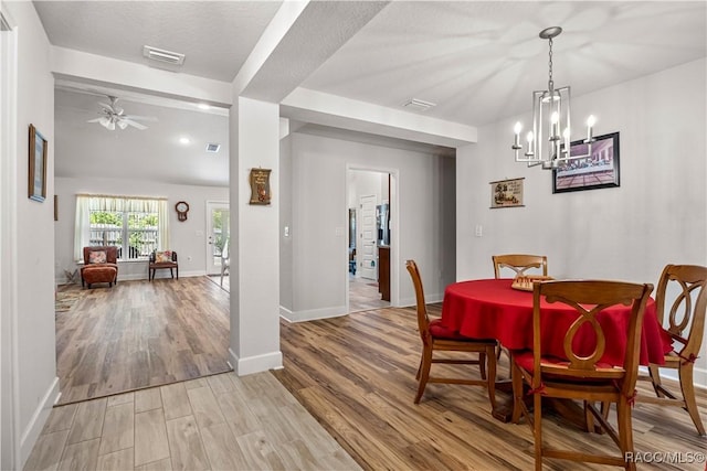 dining space with baseboards, light wood-style floors, visible vents, and ceiling fan with notable chandelier