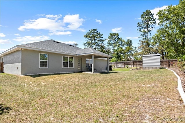 rear view of house featuring stucco siding, a yard, and fence