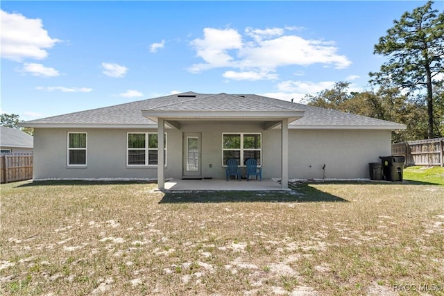 back of house featuring a patio area, fence, a yard, stucco siding, and roof with shingles