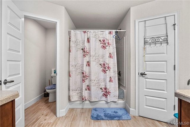 full bath with toilet, baseboards, wood finished floors, shower / tub combo with curtain, and vanity