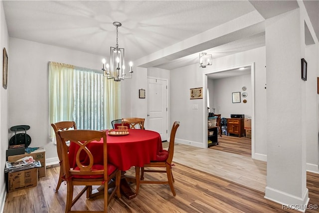 dining space with a chandelier, light wood-type flooring, and baseboards