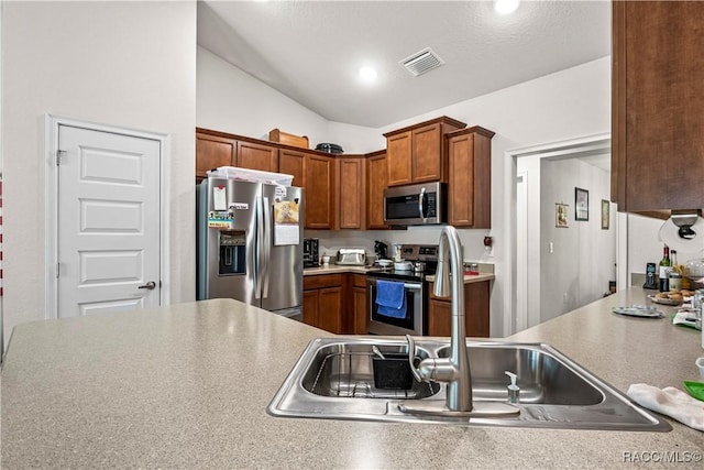 kitchen featuring a sink, light countertops, lofted ceiling, appliances with stainless steel finishes, and visible vents