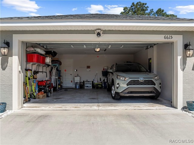 garage with concrete driveway, a garage door opener, and a sink