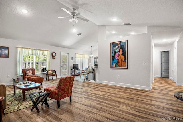 living area featuring lofted ceiling, wood finished floors, and visible vents