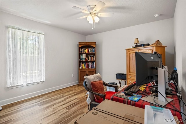 office space with baseboards, a ceiling fan, and light wood-style floors