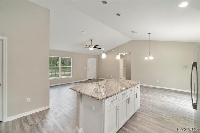 kitchen with white cabinets, light wood finished floors, light stone counters, and vaulted ceiling