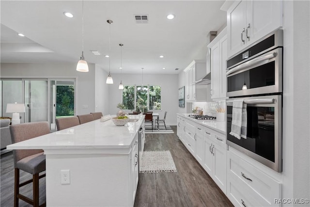 kitchen with a kitchen bar, stainless steel appliances, a kitchen island, and white cabinets