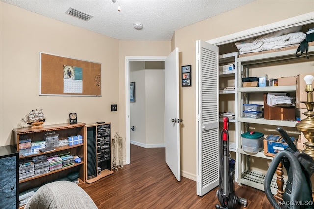 office space featuring baseboards, visible vents, dark wood finished floors, and a textured ceiling