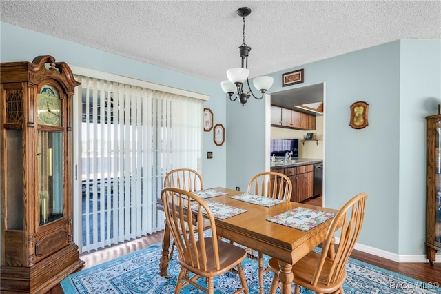 dining room with baseboards, a textured ceiling, a chandelier, and wood finished floors