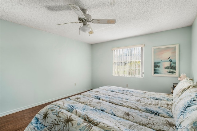 bedroom featuring dark wood finished floors, a textured ceiling, baseboards, and ceiling fan