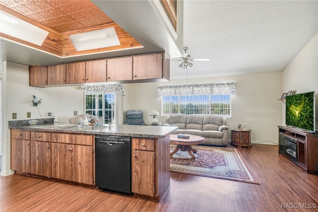 kitchen featuring black dishwasher, a tray ceiling, open floor plan, and wood finished floors