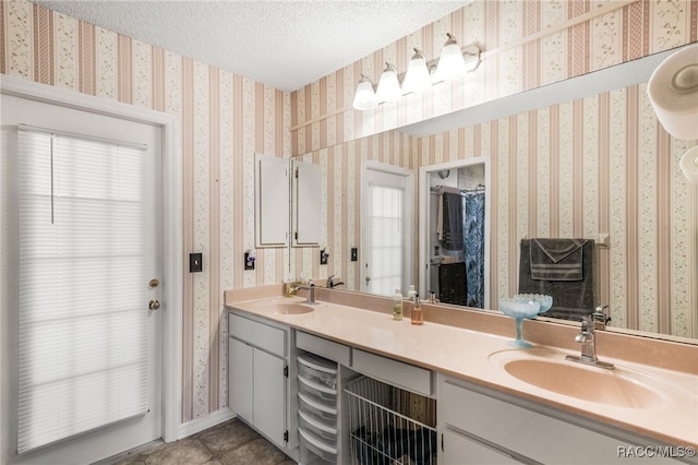 full bathroom featuring a sink, wallpapered walls, and a textured ceiling