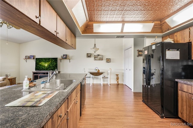 kitchen with visible vents, brown cabinetry, black fridge with ice dispenser, light wood-style flooring, and stainless steel dishwasher