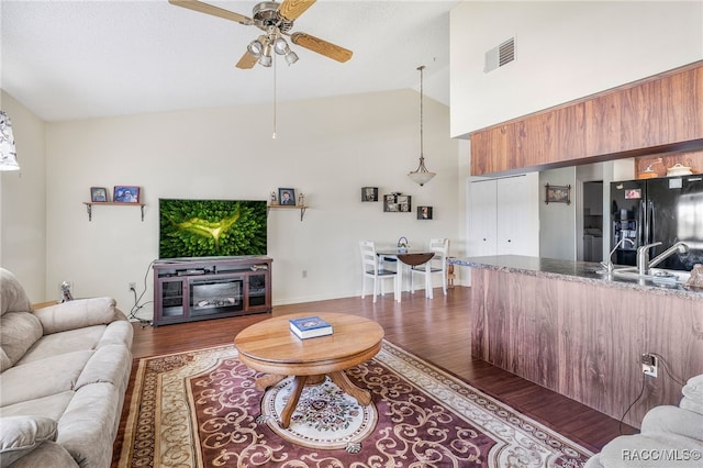 living room featuring high vaulted ceiling, a ceiling fan, visible vents, and dark wood-style flooring