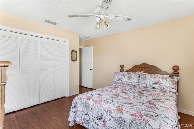 bedroom with a textured ceiling, visible vents, dark wood finished floors, and a closet