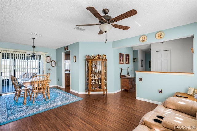 dining space with baseboards, visible vents, dark wood-style flooring, a textured ceiling, and ceiling fan with notable chandelier