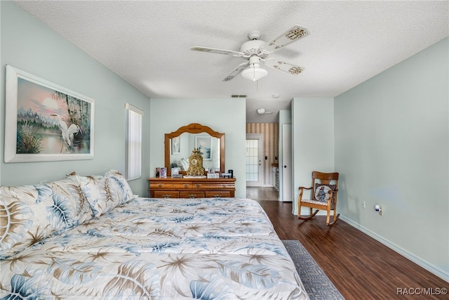 bedroom with a textured ceiling, ceiling fan, dark wood-style flooring, visible vents, and baseboards