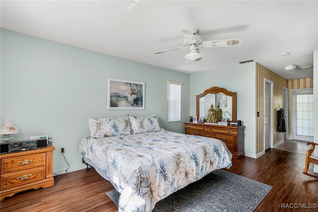 bedroom featuring ceiling fan, a textured ceiling, baseboards, and dark wood-style flooring