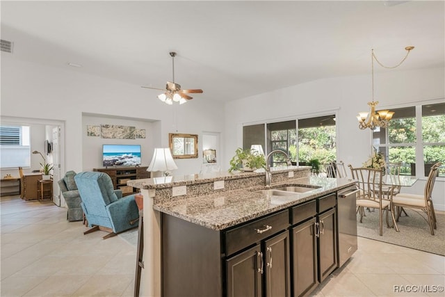 kitchen with sink, a kitchen island with sink, stainless steel dishwasher, light stone counters, and dark brown cabinets