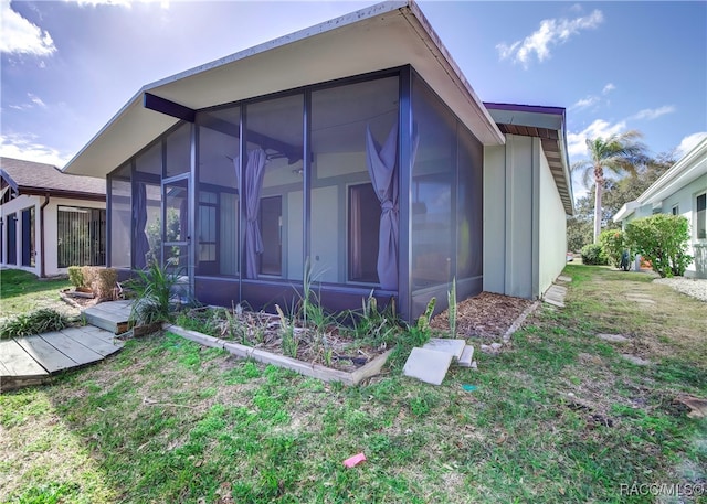 view of side of home with a lawn and a sunroom