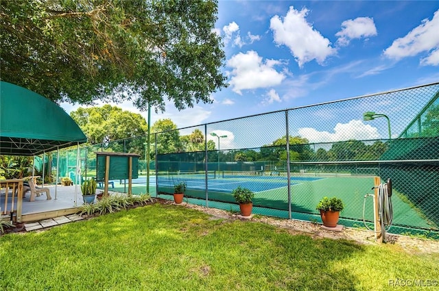 view of tennis court featuring a lawn