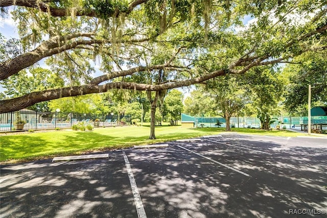 view of property's community with tennis court and a yard