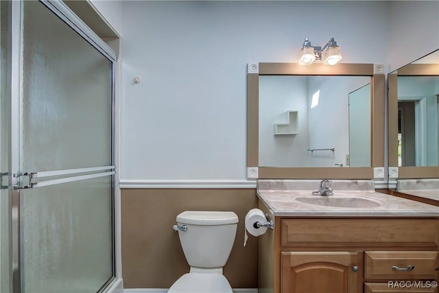 bathroom with a shower with shower door, toilet, and vanity