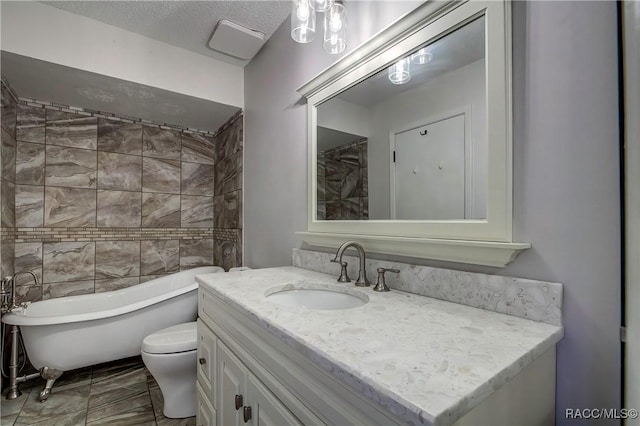 bathroom featuring toilet, a textured ceiling, a tub to relax in, and vanity