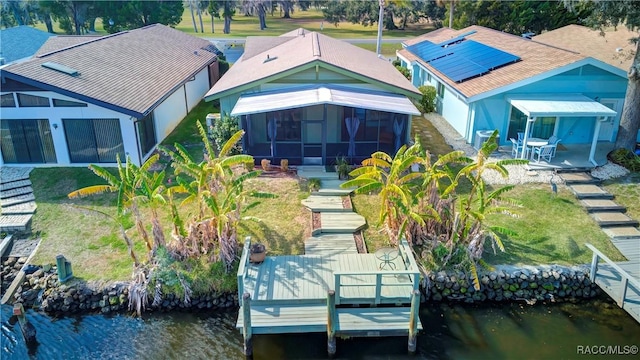 rear view of property with a water view, a lawn, and a sunroom