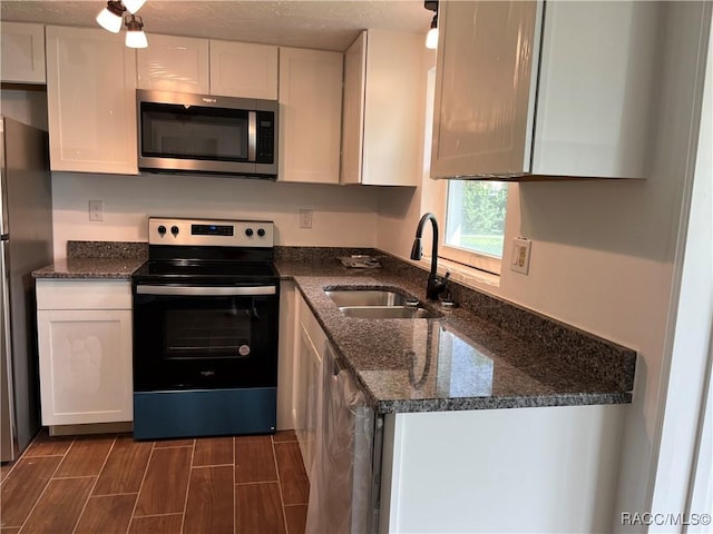 kitchen featuring sink, white cabinets, dark stone counters, and appliances with stainless steel finishes