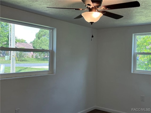 empty room featuring ceiling fan, a healthy amount of sunlight, and a textured ceiling