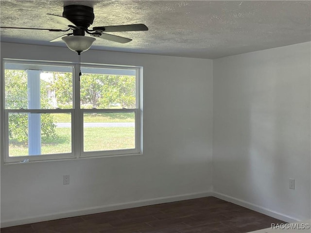 unfurnished room with ceiling fan, dark hardwood / wood-style flooring, and a textured ceiling