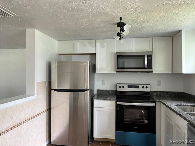 kitchen with appliances with stainless steel finishes, a textured ceiling, and white cabinetry