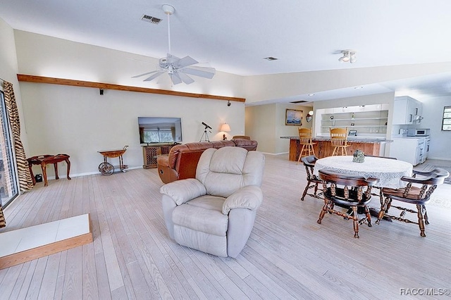 living room with visible vents, baseboards, lofted ceiling, light wood-style flooring, and ceiling fan