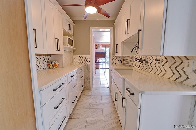 kitchen with tasteful backsplash, marble finish floor, light countertops, and white microwave