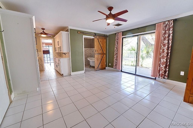 unfurnished room with light tile patterned floors, a barn door, visible vents, and ornamental molding