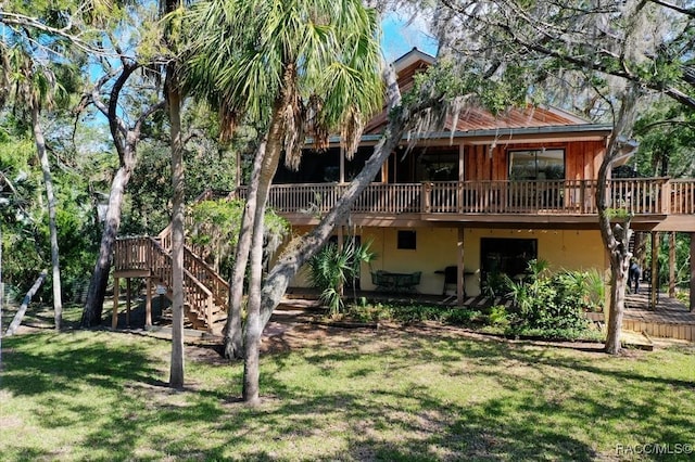 back of property featuring a deck, a lawn, stairs, and stucco siding