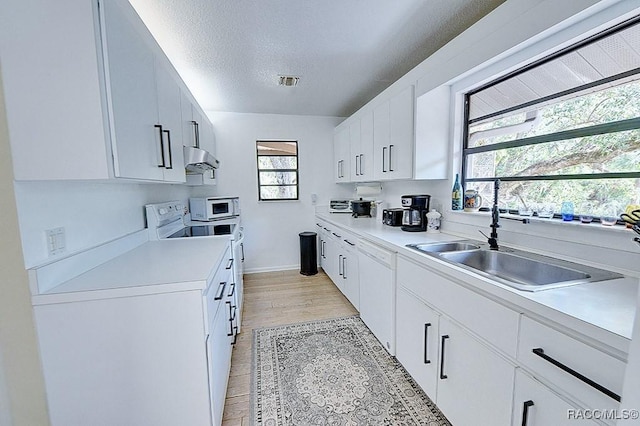 kitchen featuring a textured ceiling, white appliances, a sink, visible vents, and light countertops