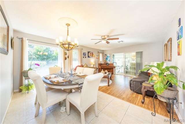 dining room with light tile patterned flooring, a healthy amount of sunlight, and ceiling fan with notable chandelier