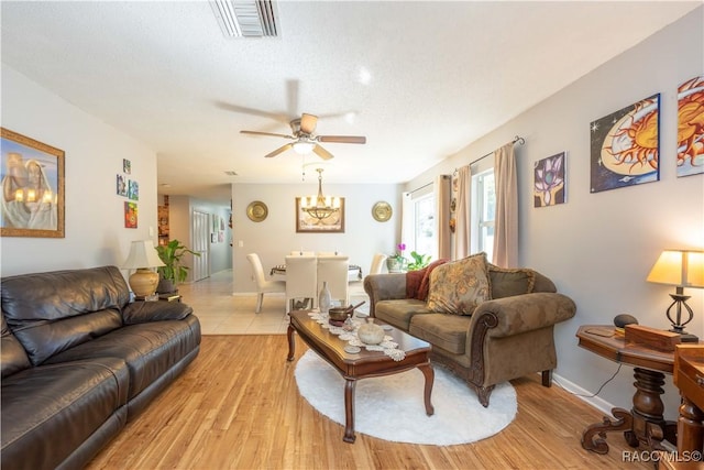 living room featuring ceiling fan, light hardwood / wood-style flooring, and a textured ceiling