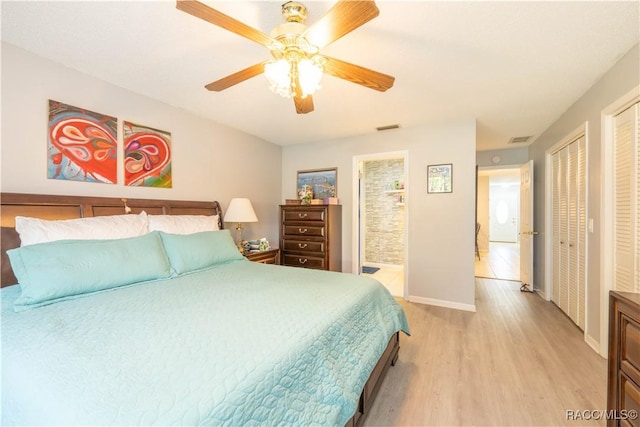 bedroom featuring connected bathroom, multiple closets, ceiling fan, and light wood-type flooring