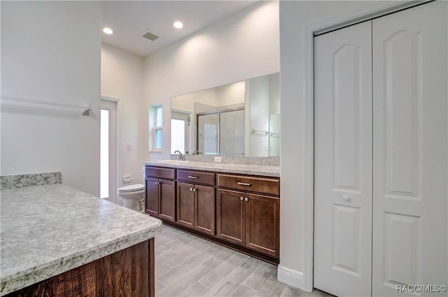 bathroom with vanity, toilet, and a shower with shower door