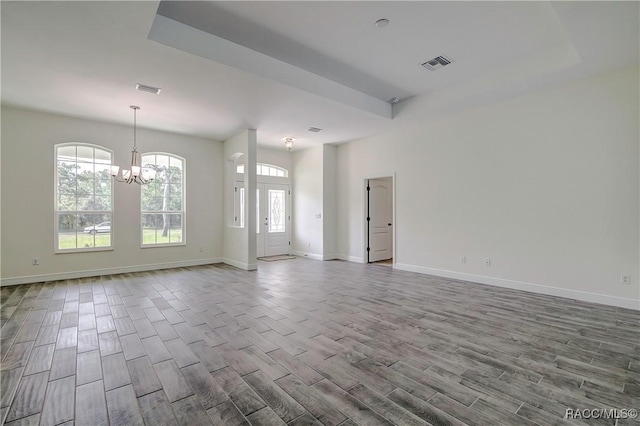 empty room featuring a tray ceiling and an inviting chandelier