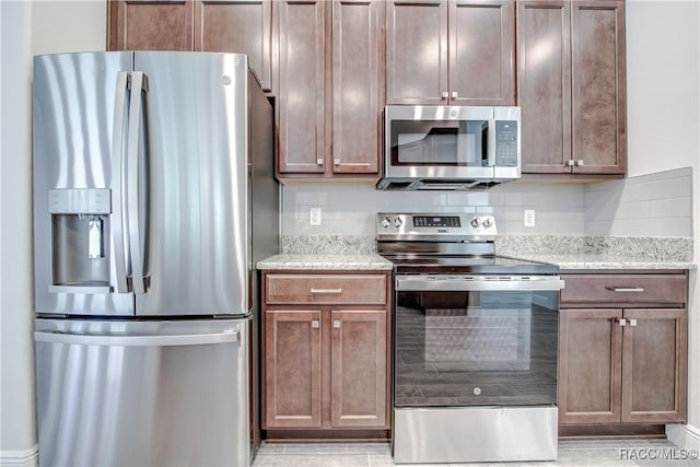 kitchen with appliances with stainless steel finishes, backsplash, and light stone counters