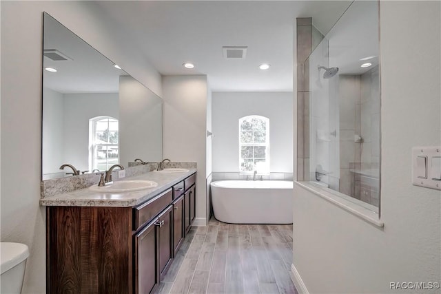 full bathroom featuring hardwood / wood-style flooring, vanity, separate shower and tub, and toilet