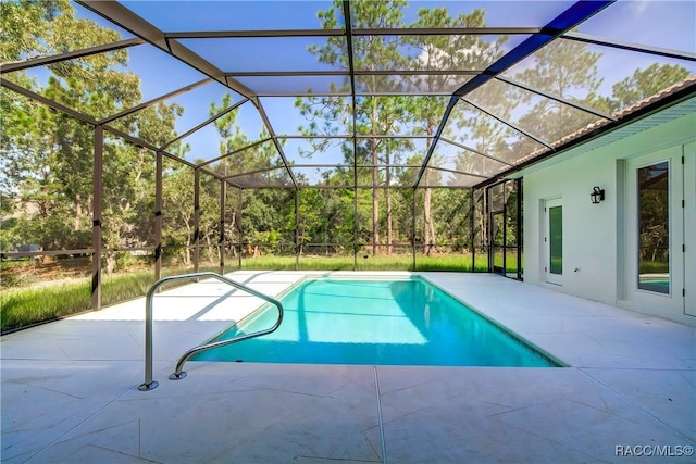 view of pool with glass enclosure and a patio